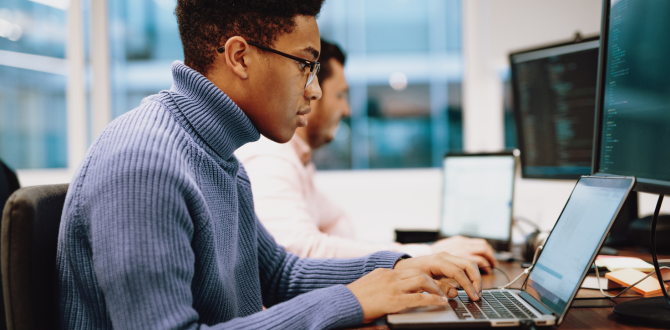 A young black boy with glasses looking at a laptop screen coding.